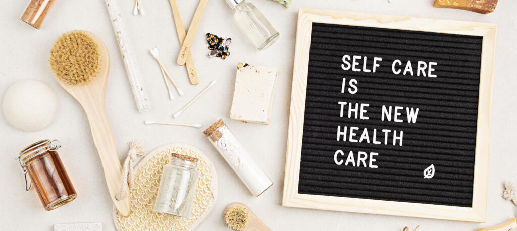 Self care is the new health care. Motivational quote on black letter board with variety of organic body and face care products. Natural homemade eco friendly beauty products
